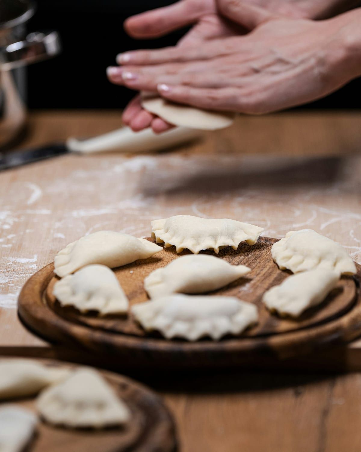 Hands folding a momo on a floured board